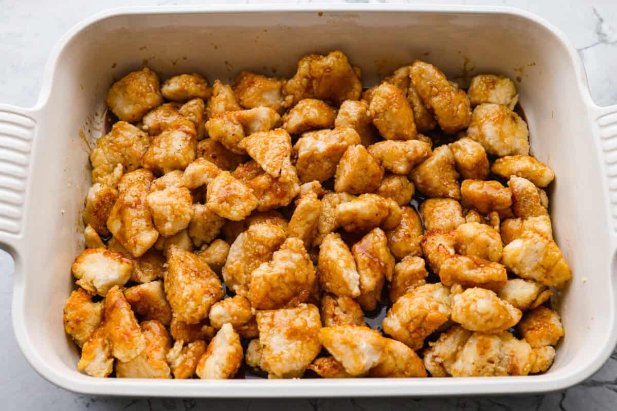 Skip the takeout and make this easy baked General Tso’s chicken at home! It’s crispy, saucy, and perfectly sweet with just the right amount of heat, no deep fryer required. Browned General Tso's chicken chicken in a baking dish with the sauce added on top.