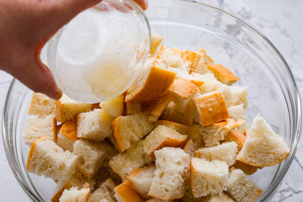 If you love classic bread pudding, you’ve got to try banana bread pudding. Sweet banana flavor, a soft custardy center, and golden edges that taste like heaven. It’s easy to throw together and is perfect for brunch or even dessert! Someone pouring melted butter over the dried bread.