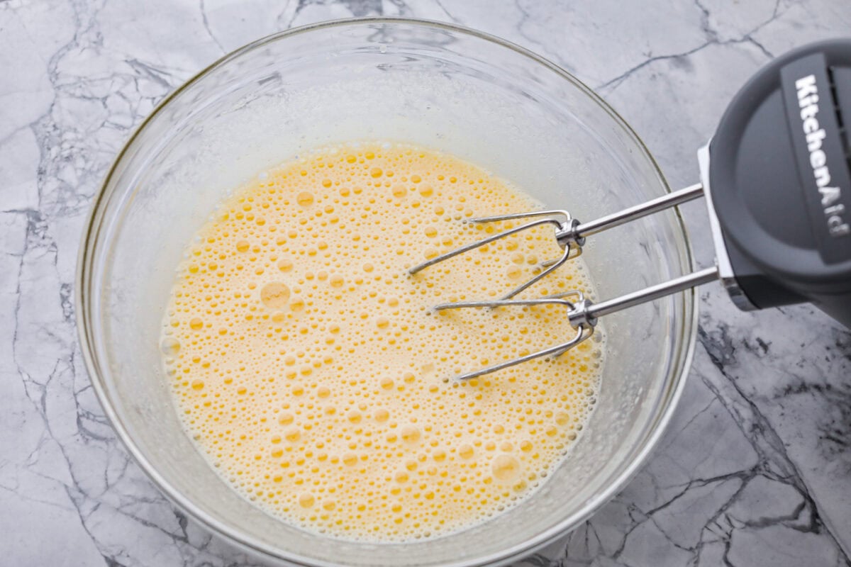 If you love classic bread pudding, you’ve got to try banana bread pudding. Sweet banana flavor, a soft custardy center, and golden edges that taste like heaven. It’s easy to throw together and is perfect for brunch or even dessert! Someone using a hand mixer to whip up the eggs and sugar.
