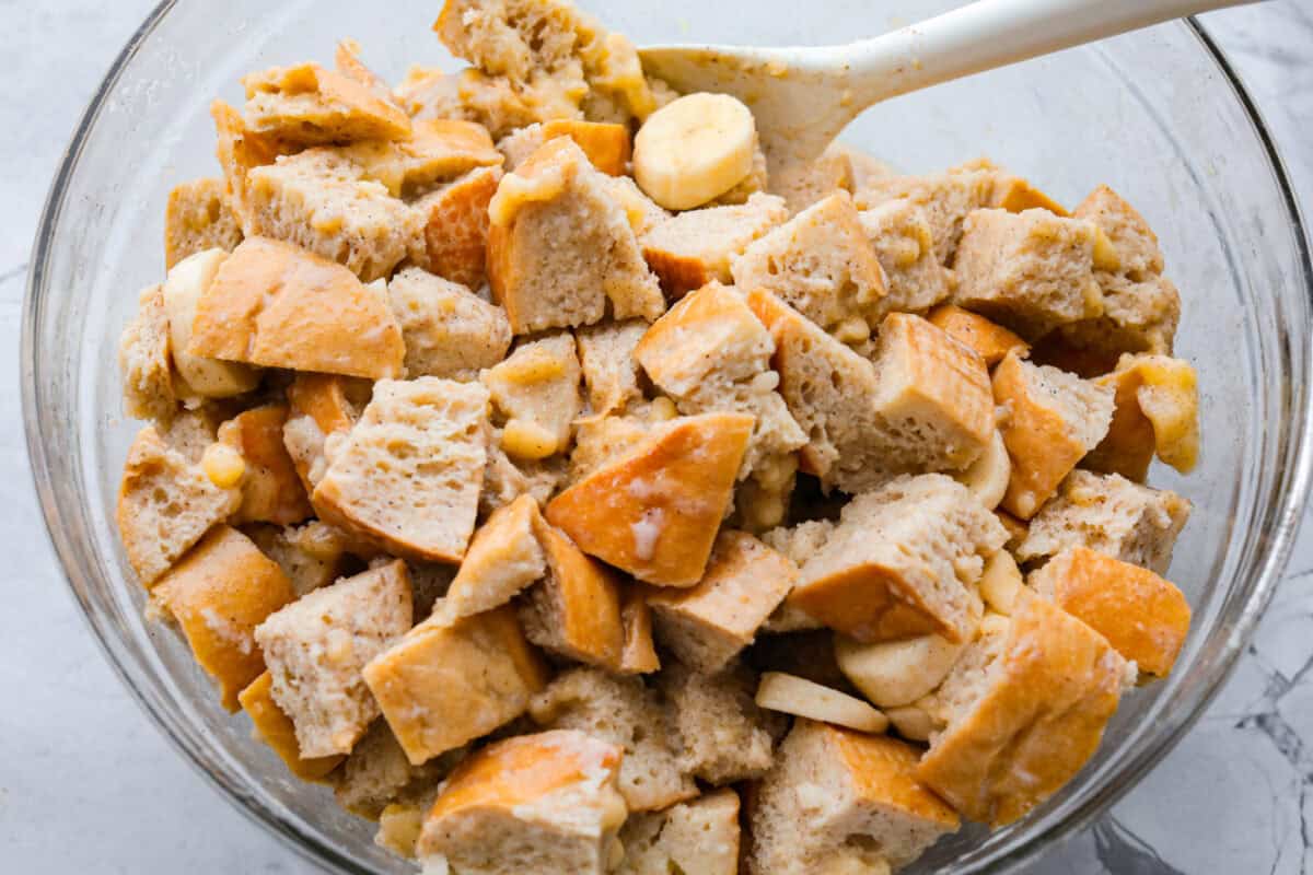 If you love classic bread pudding, you’ve got to try banana bread pudding. Sweet banana flavor, a soft custardy center, and golden edges that taste like heaven. It’s easy to throw together and is perfect for brunch or even dessert! Someone stirring the milk mixture into the bread and bananas.