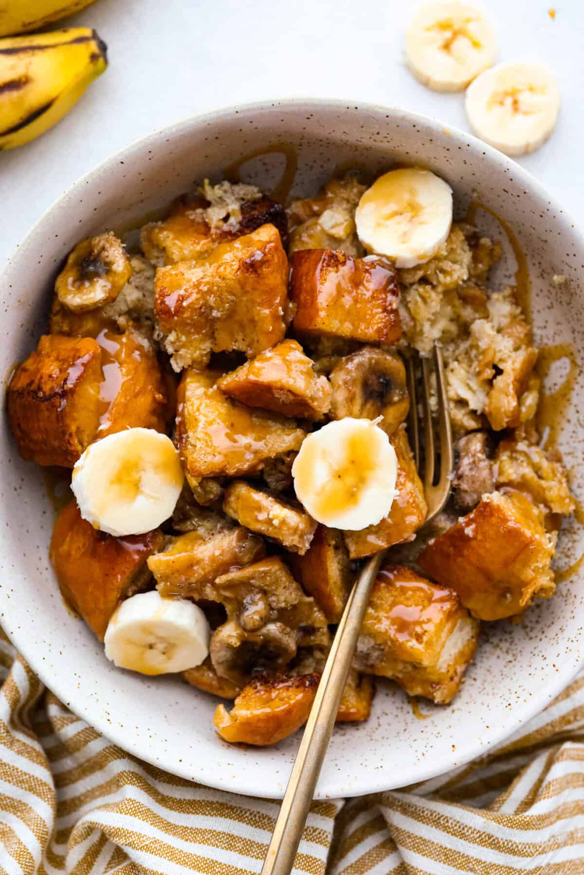 If you love classic bread pudding, you’ve got to try banana bread pudding. Sweet banana flavor, a soft custardy center, and golden edges that taste like heaven. It’s easy to throw together and is perfect for brunch or even dessert! Bowl with a serving size of the banana bread pudding.