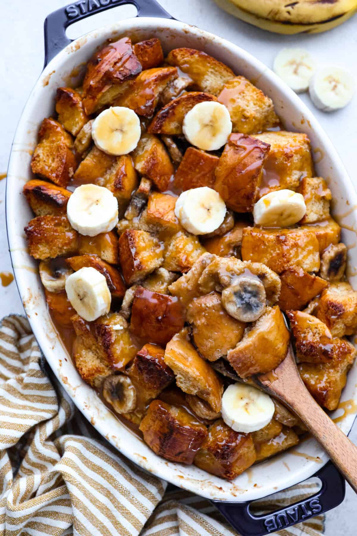If you love classic bread pudding, you’ve got to try banana bread pudding. Sweet banana flavor, a soft custardy center, and golden edges that taste like heaven. It’s easy to throw together and is perfect for brunch or even dessert! Overhead shot of cooked banana bread pudding drizzled with caramel and topped with sliced fresh bananas.