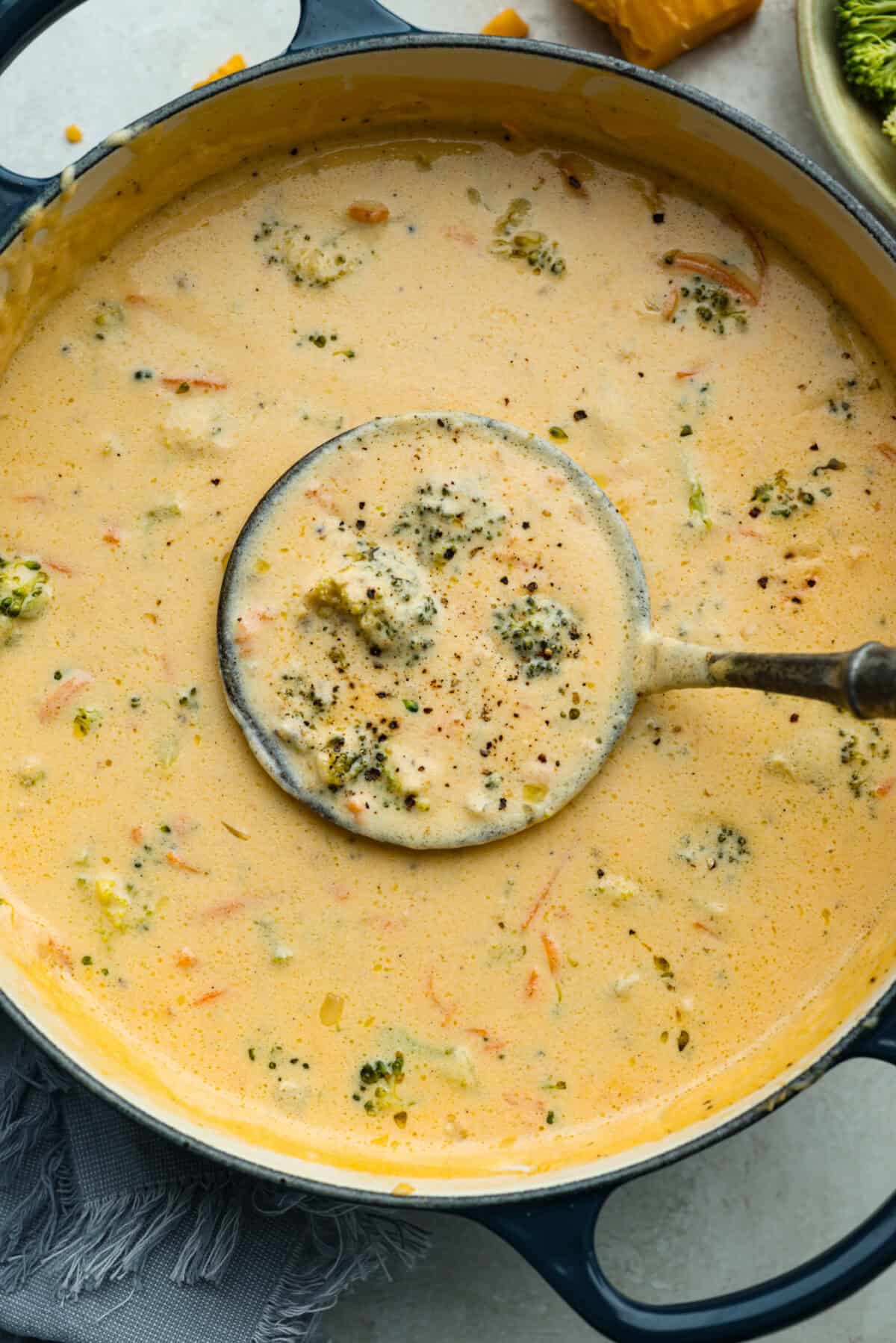 Overhead shot of Panera broccoli cheddar soup in a pot with a ladel.