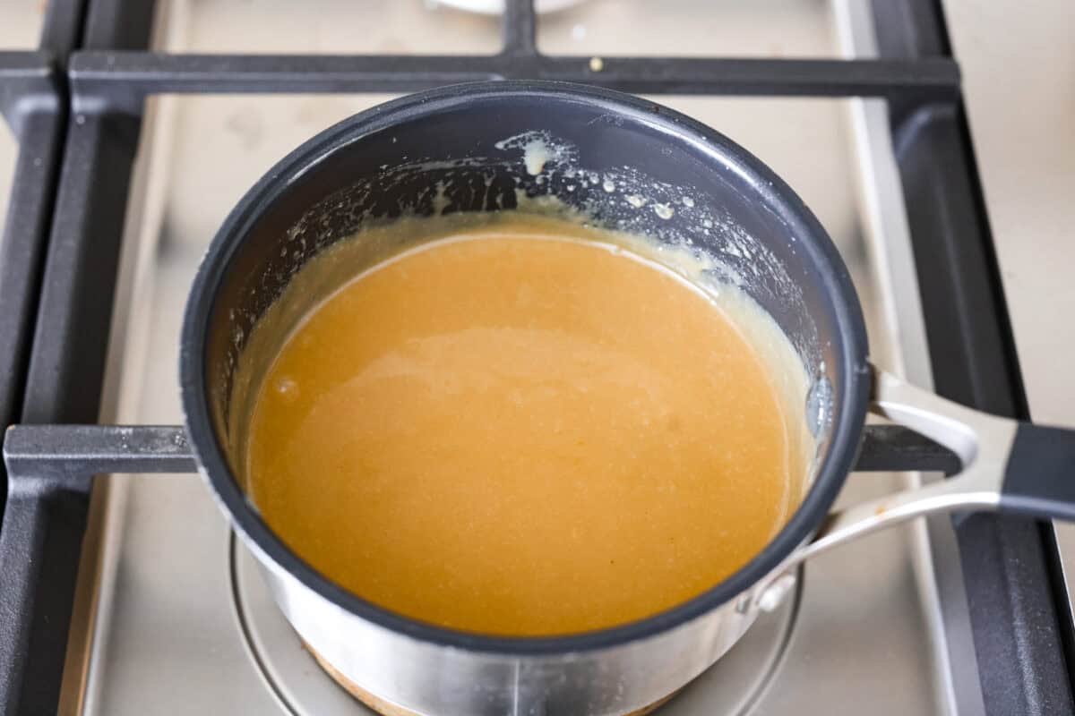 These Caramel Apple Cinnamon Rolls are soft, gooey, and baked with cozy fall flavor in every bite. The homemade dough bakes up perfectly fluffy, and the rich caramel topping makes them feel extra special. Caramel apple cinnamon roll glaze in a pan.