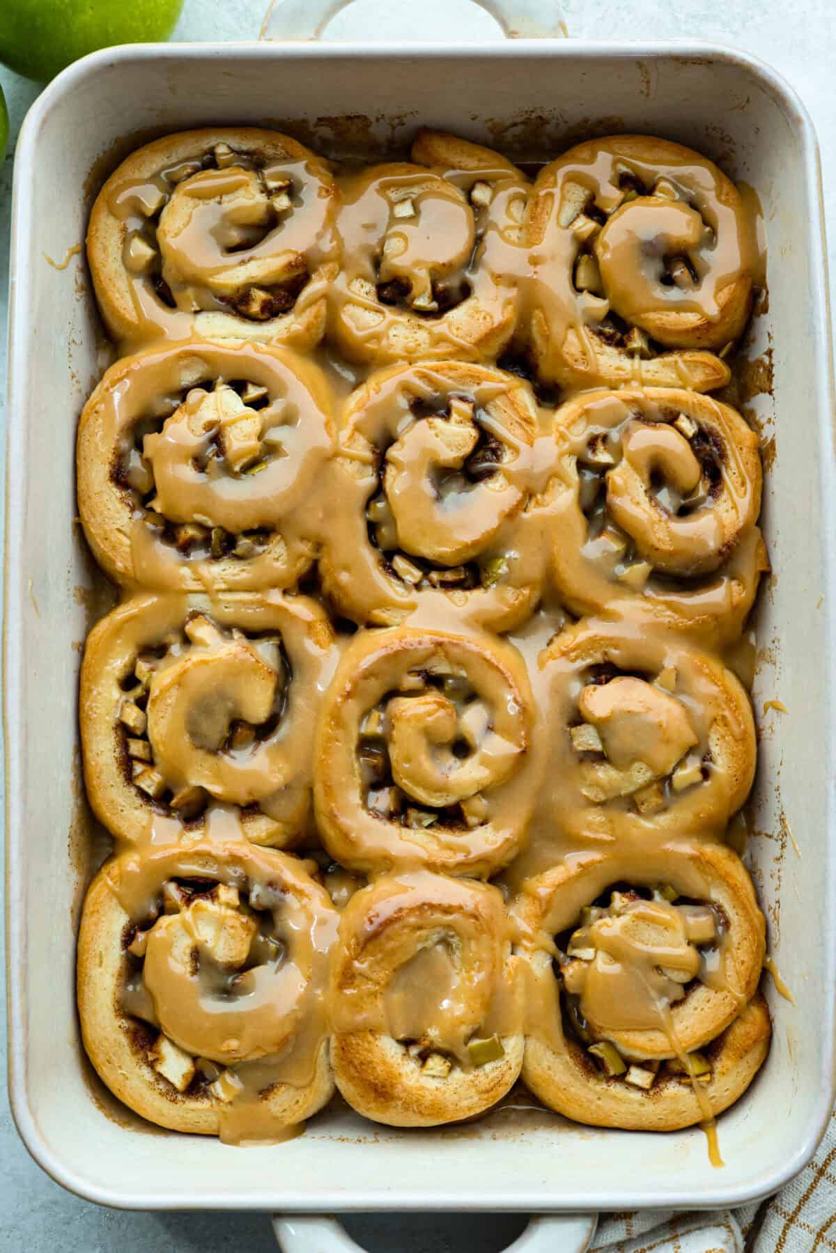 These Caramel Apple Cinnamon Rolls are soft, gooey, and baked with cozy fall flavor in every bite. The homemade dough bakes up perfectly fluffy, and the rich caramel topping makes them feel extra special. Overhead shot of baked and glazed caramel apple cinnamon rolls.
