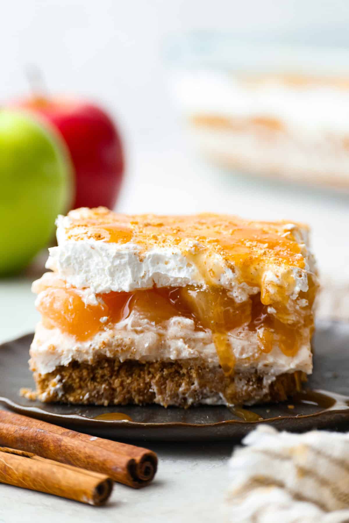 Caramel Apple Pie Lush is the easiest fall dessert you’ll ever make! With layers of buttery crust, creamy cheesecake, spiced apples, caramel, and whipped topping, it’s a yummy fall treat that is so much easier than baking a pie from scratch! Side shot of a piece of caramel apple pie lush.