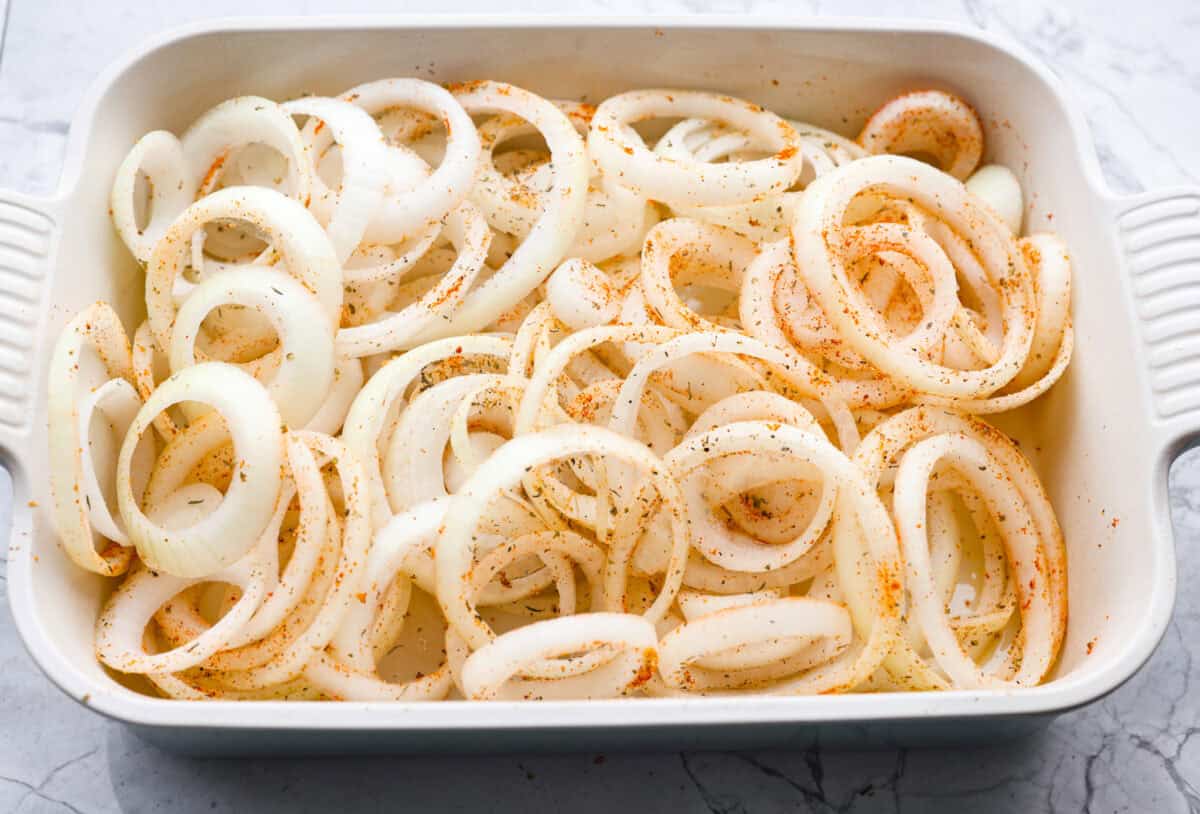 If you’ve never had Tennessee onions, bless your heart! Sweet onions bake in butter and gooey cheese until they’re golden, bubbly, and downright sinful. The perfect side to complement steak, chicken, burgers, or your favorite BBQ. Seasoned onions spread out in a 9x13 baking dish.