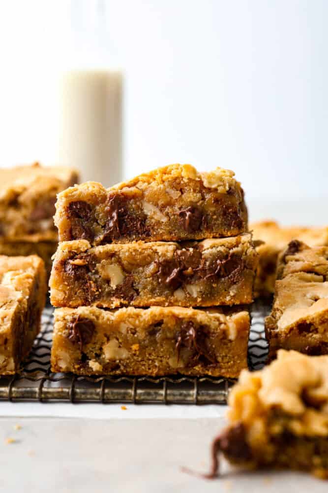 If you’ve never tried a congo bar, they’re basically chocolate chip cookie bars with a little added flair. They’re usually made with chopped nuts or coconut for some extra texture, and let me tell you… They are what dreams are made of. Stack of congo bars on a cooling rack.