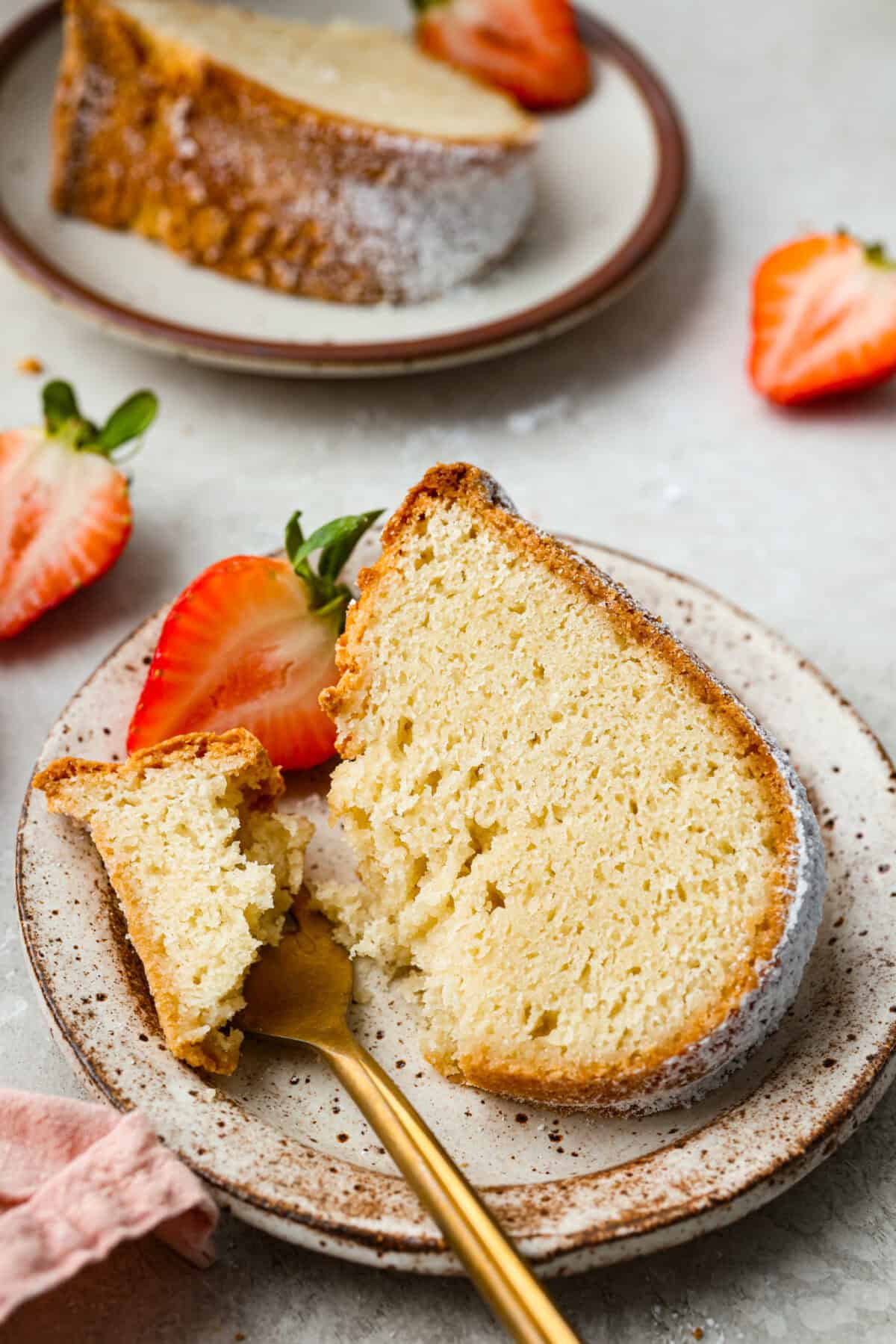 This sour cream pound cake is buttery, moist, and so tender. The light vanilla flavor with a little tang from the sour cream makes it delicious on its own, or even better with berries, whipped cream, or ice cream. Plated slice of sour cream pound cake garnished with a strawberry.