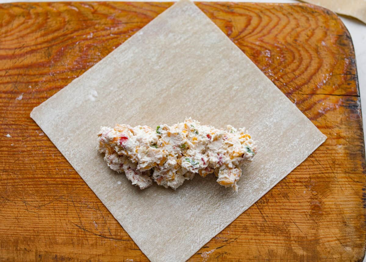 Crack Chicken Egg Rolls wrap savory chicken, crispy bacon, melty cheese, and zesty ranch in a golden, crunchy shell. Easy to make, lighter than deep-fried versions, and perfect for parties or game day! Egg roll wrapper with a scoop of filling on it.