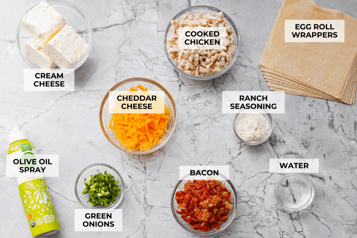 Crack Chicken Egg Rolls wrap savory chicken, crispy bacon, melty cheese, and zesty ranch in a golden, crunchy shell. Easy to make, lighter than deep-fried versions, and perfect for parties or game day! Overhead shot of labeled ingredients.