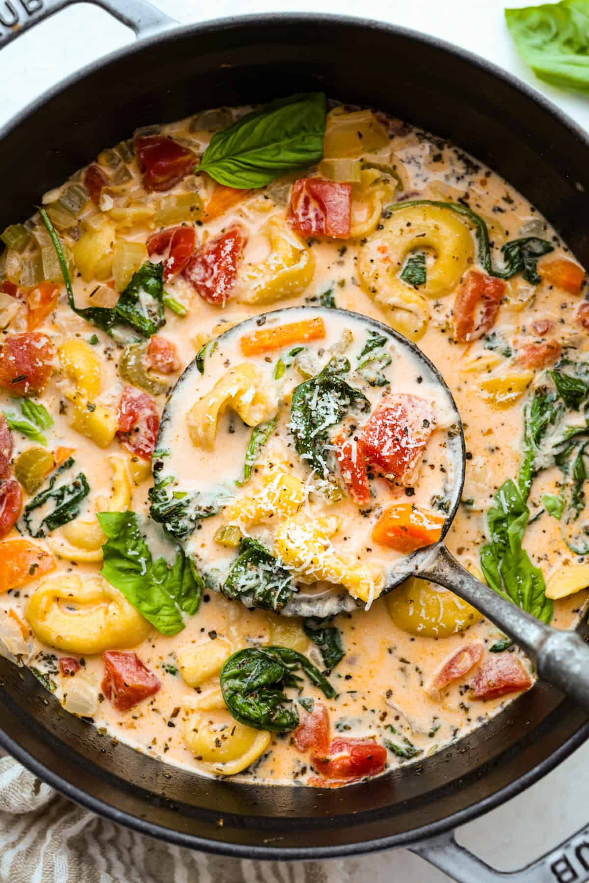 My love of cozy soups kicks in the second summer fades. This creamy tortellini soup gives me all the fall vibes. Fresh veggies, cheesy pasta, and a creamy broth, it's comfort in a bowl. You’ve got to try it today! Pot of creamy vegetable tortellini soup with a silver ladle.