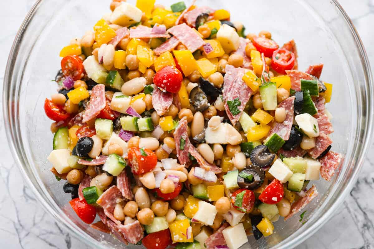 TikTok creator Violet Witchel made this dense bean salad go viral for good reason. It’s simple, high in fiber, protein-packed, and stays delicious for days. My version keeps the same hearty texture and zesty flavor that made her trend explode. Large bowl of dense bean salad ingredients all mixed together.