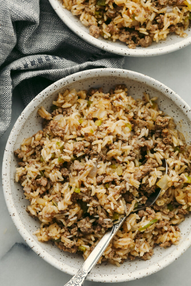 Why is it called “dirty” rice? The rice gets brown as it cooks with meat, Cajun spices, and the holy trinity of Cajun cooking: onion, bell pepper, and celery. My version combines ground pork and beef for a flavorful twist on this Louisiana classic! Dirty rice in a bowl with a spoon.