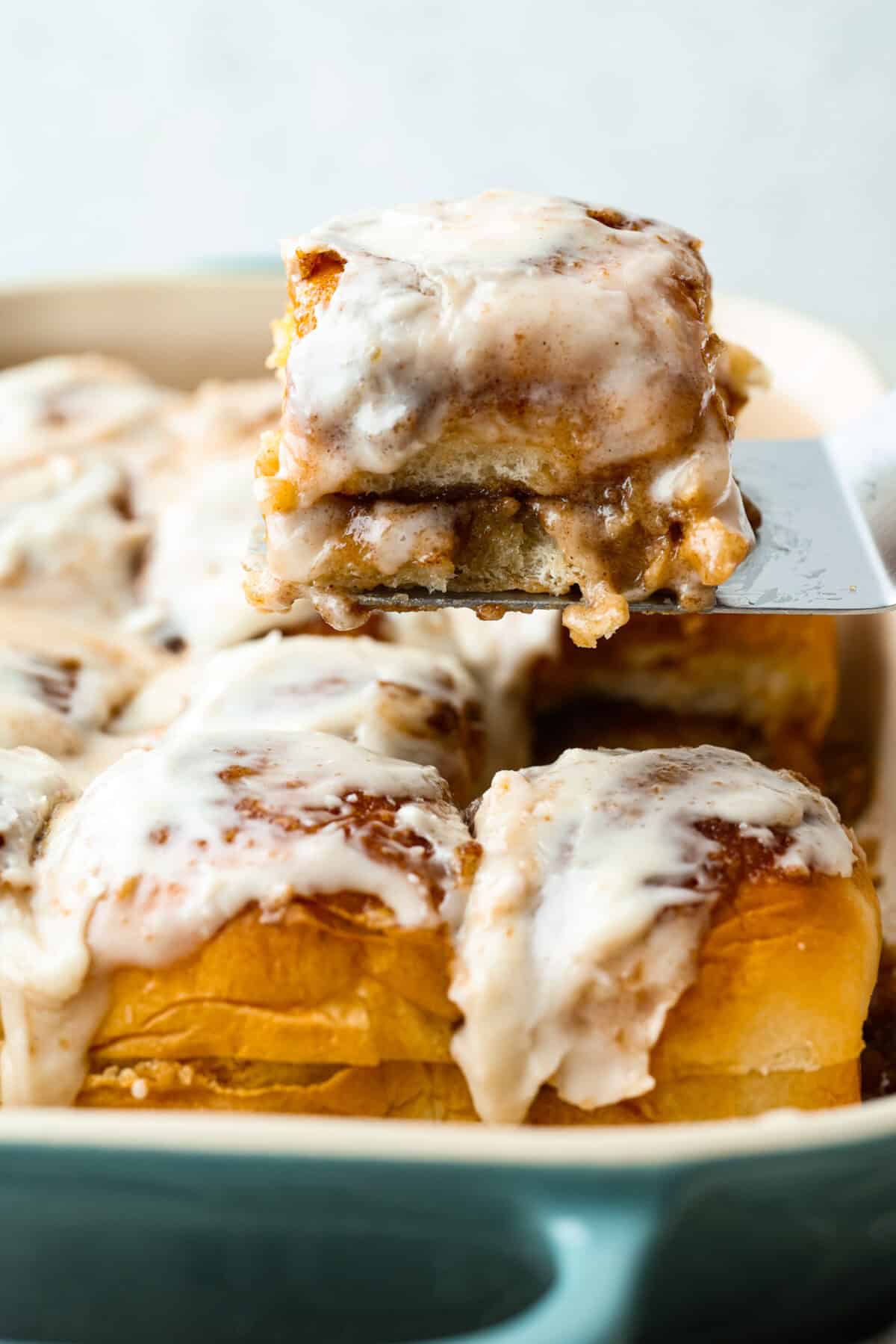 Sometimes you just need warm, gooey cinnamon rolls without the hours of waiting. These Hawaiian Roll Cinnamon Rolls are the cozy little hack that bring all the cinnamon-sugar joy with half the effort. Someone lifting a Hawaiian roll cinnamon roll out of the pan.