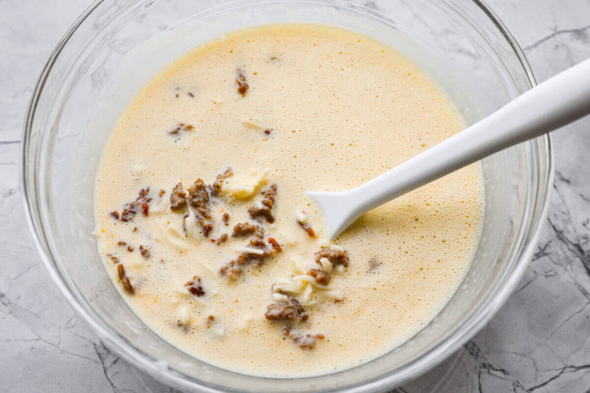 In a blender, add the eggs, cottage cheese, salt, pepper, and dried basil. Cooked sausage, sun-dried tomatoes, and shredded cheese added to the egg mixture.