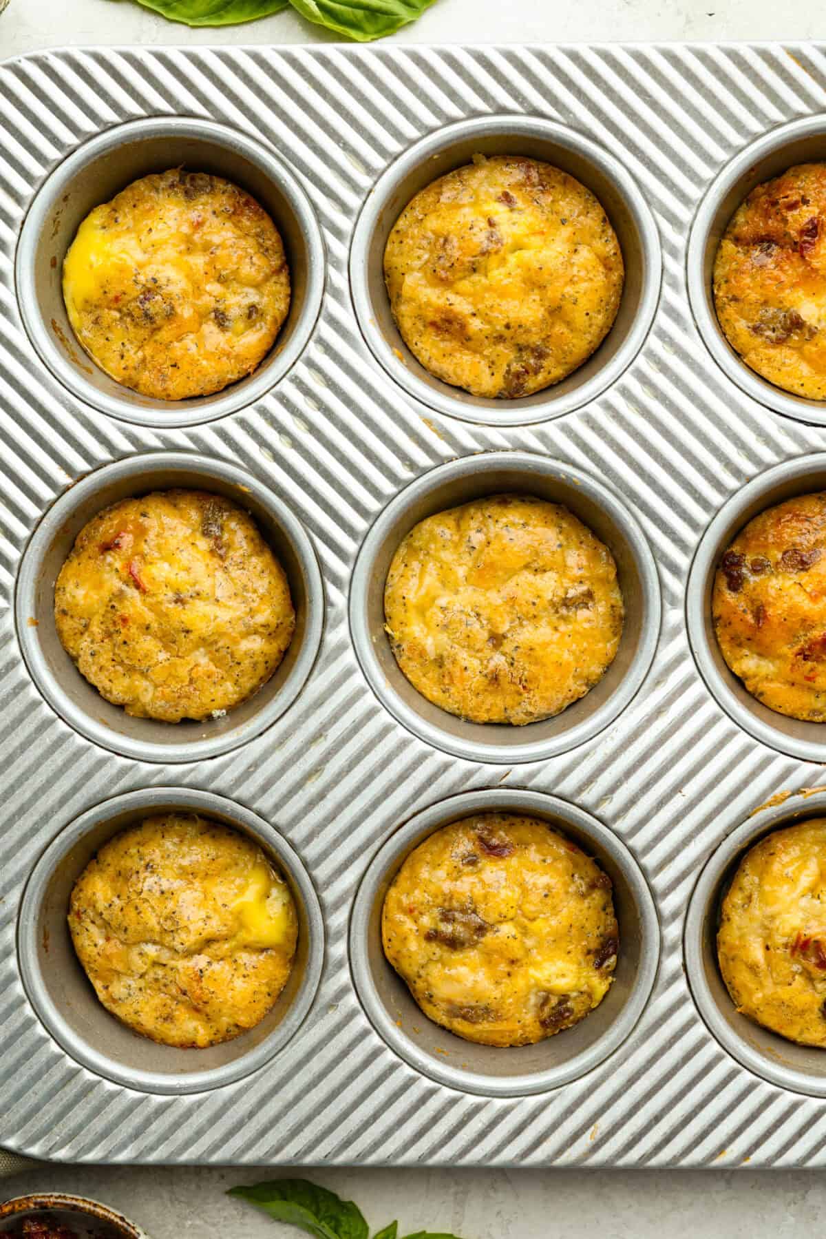 Use a measuring cup to scoop the egg mixture into the wells of the muffin tin, filling them no more than ⅔ of the way full. Try to disperse the sausage evenly throughout the muffin wells. Overhead shot of Starbucks copycat Italian sausage egg bites cooked in muffin tin.
