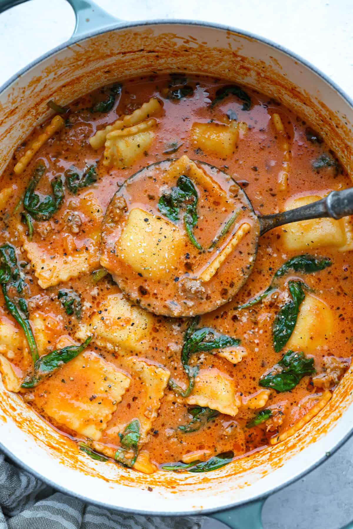 Million Dollar Soup is creamy, comforting, and worth every indulgent bite! The rich tomato soup base is loaded with sausage, cheesy ravioli, and heavy cream. The dollop of ricotta cheese on top is a MUST! Pot of million dollar soup.