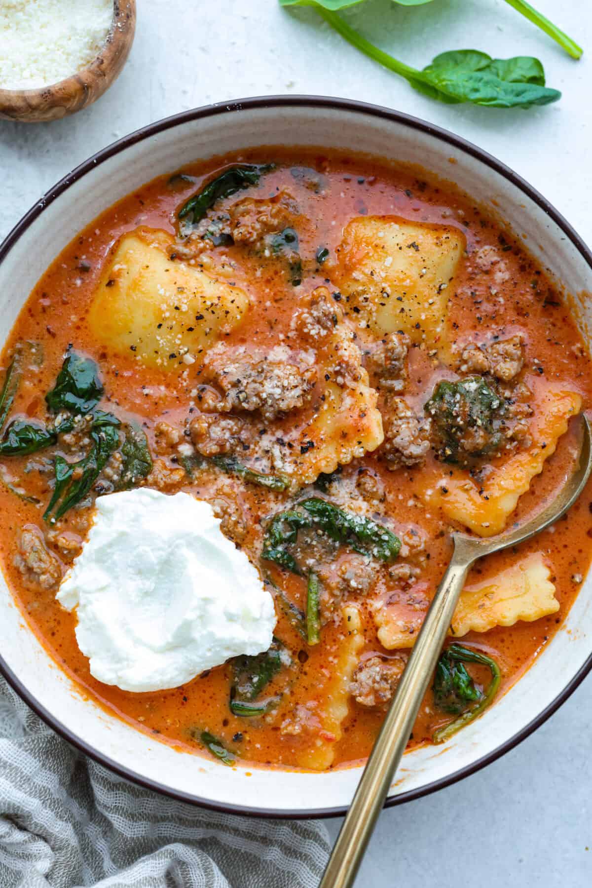 Million Dollar Soup is creamy, comforting, and worth every indulgent bite! The rich tomato soup base is loaded with sausage, cheesy ravioli, and heavy cream. The dollop of ricotta cheese on top is a MUST! Bowl of million dollar soup with a dollop of ricotta cheese.