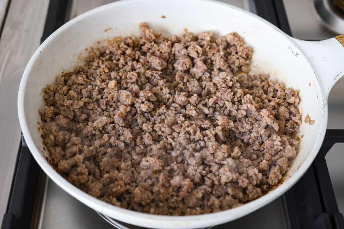 Forget the usual biscuits and gravy, this version takes everything you love and turns it into one irresistible, bubbly casserole. Creamy sausage gravy, buttery biscuits, and zero stress. Sausage cooking in a skillet.