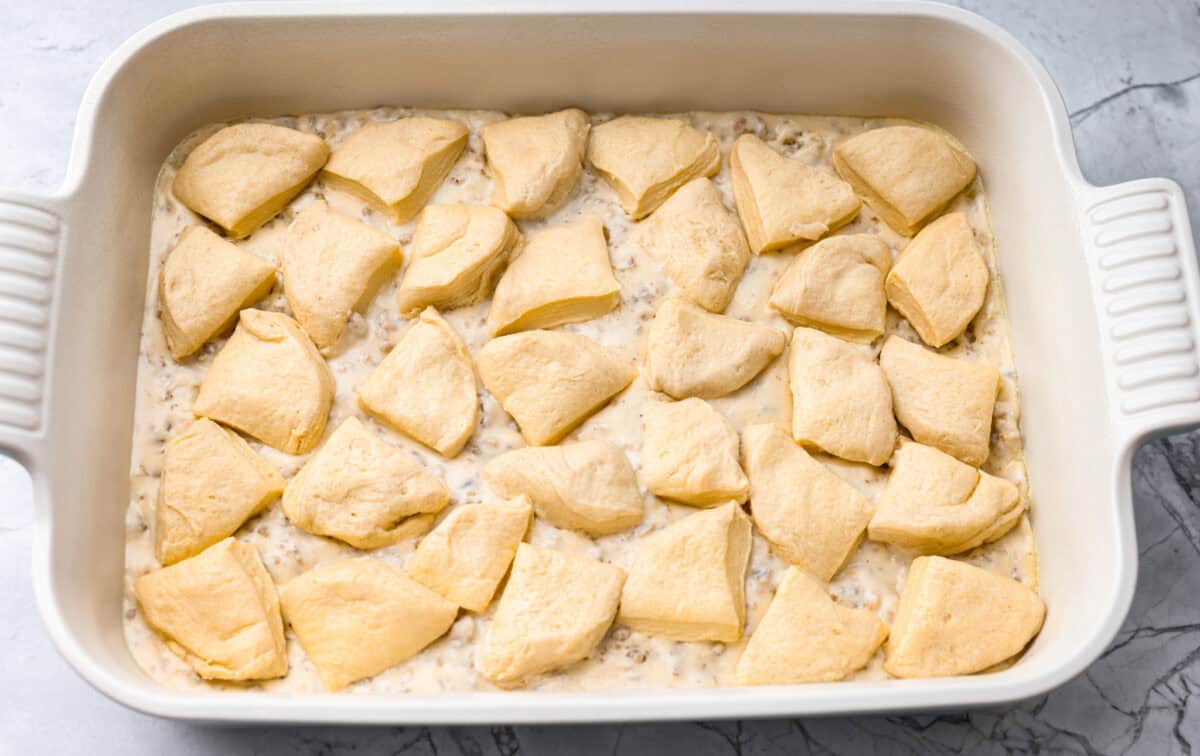 Forget the usual biscuits and gravy, this version takes everything you love and turns it into one irresistible, bubbly casserole. Creamy sausage gravy, buttery biscuits, and zero stress. Pieces of the cut up biscuits on top of the sausage gravy.