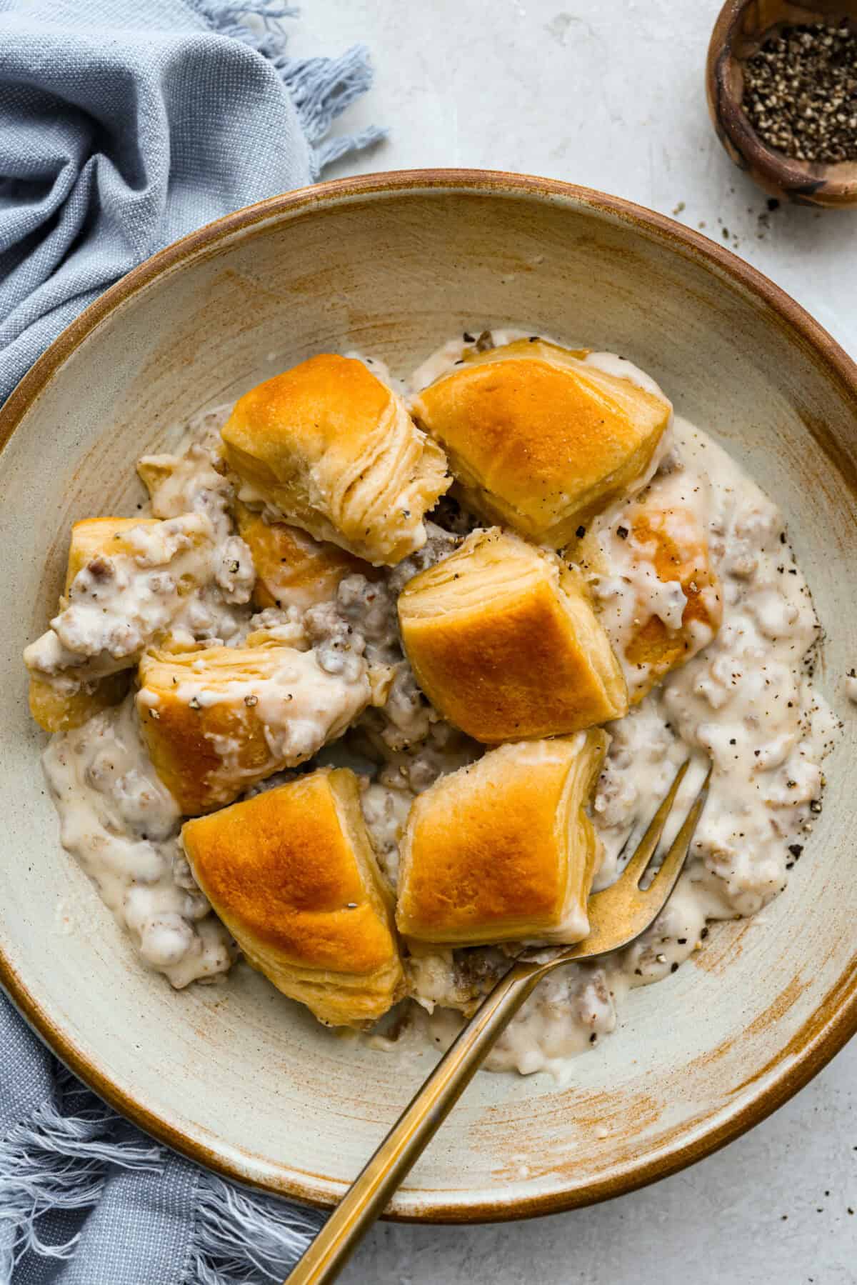 Forget the usual biscuits and gravy, this version takes everything you love and turns it into one irresistible, bubbly casserole. Creamy sausage gravy, buttery biscuits, and zero stress. Bowl with a serving of biscuits and gravy casserole.