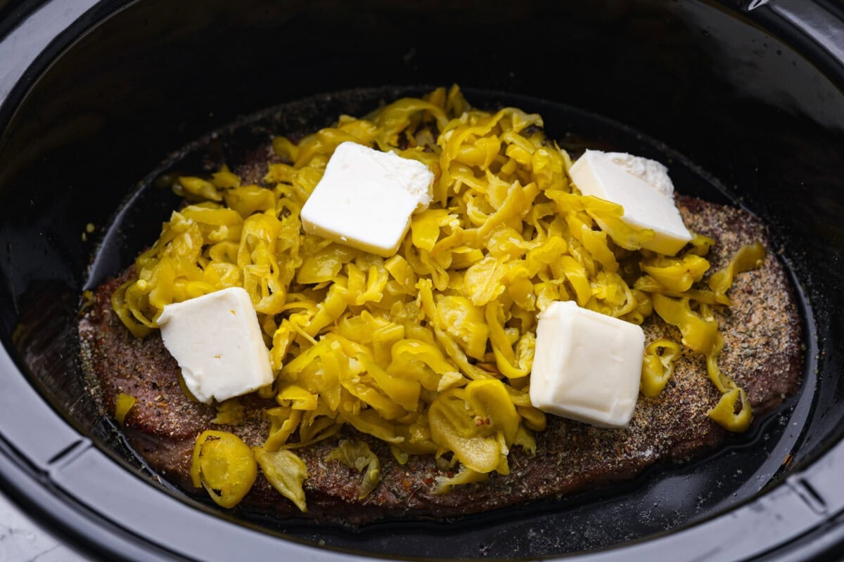 My Slow Cooker Italian Beef is tender, juicy, and loaded with zesty Italian flavor. The secret's in the way you sear the beef! This creates melt-in-your-mouth meat perfect for sandwiches or hearty dinners. Ingredients added to the top of the beef in the crockpot.