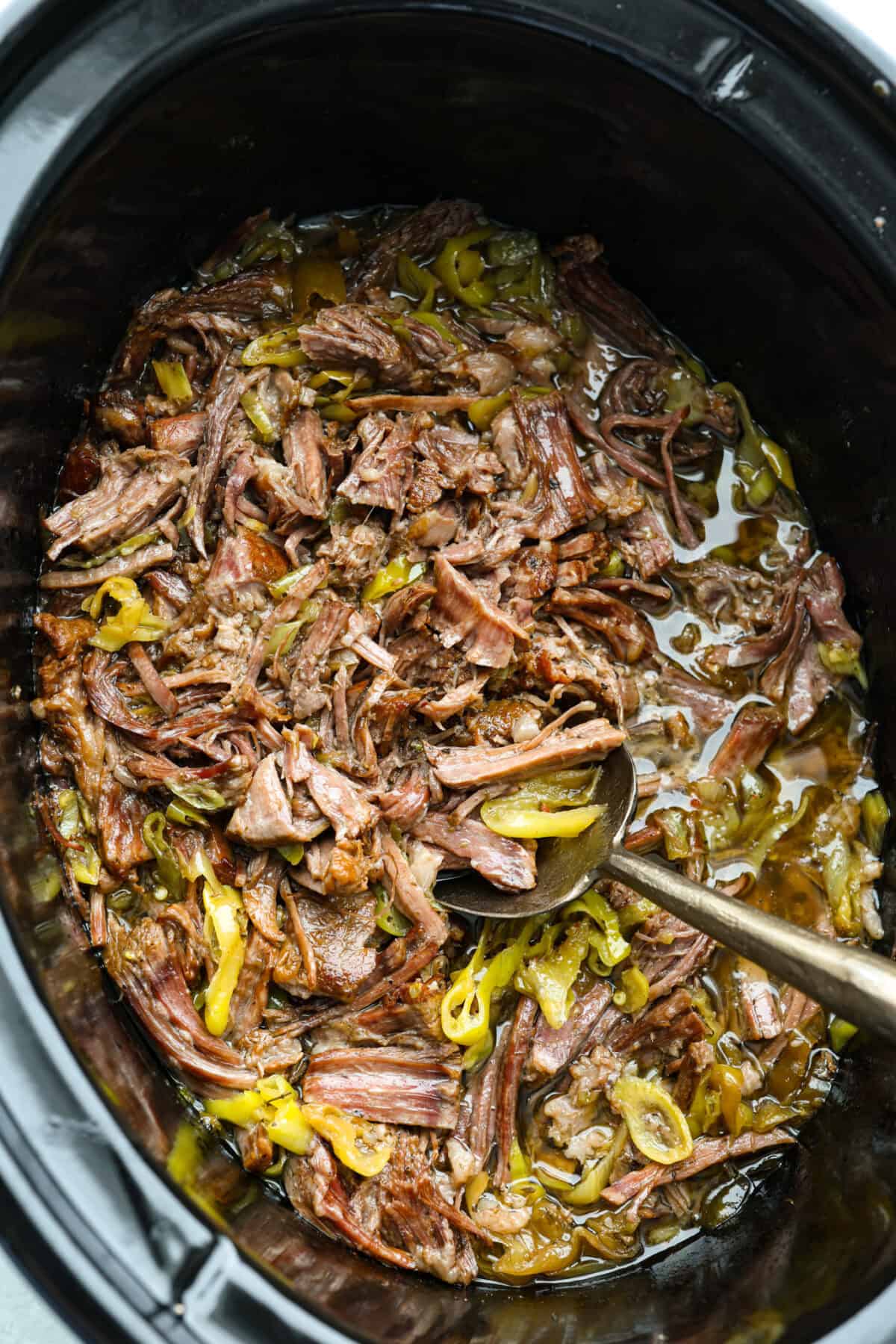 My Slow Cooker Italian Beef is tender, juicy, and loaded with zesty Italian flavor. The secret's in the way you sear the beef! This creates melt-in-your-mouth meat perfect for sandwiches or hearty dinners. Crockpot with slow cooker Italian beef cooked and shredded inside.