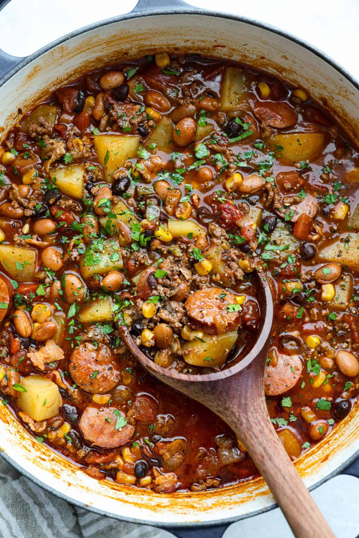 My Texas Cowboy Stew actually fills up my always-hungry boys! That's because it's loaded with smoky bacon, spicy sausage, ground beef, and potatoes. They all simmer together in a rich broth for a hearty stew. Overhead shot of a pot of Texas Cowboy Stew