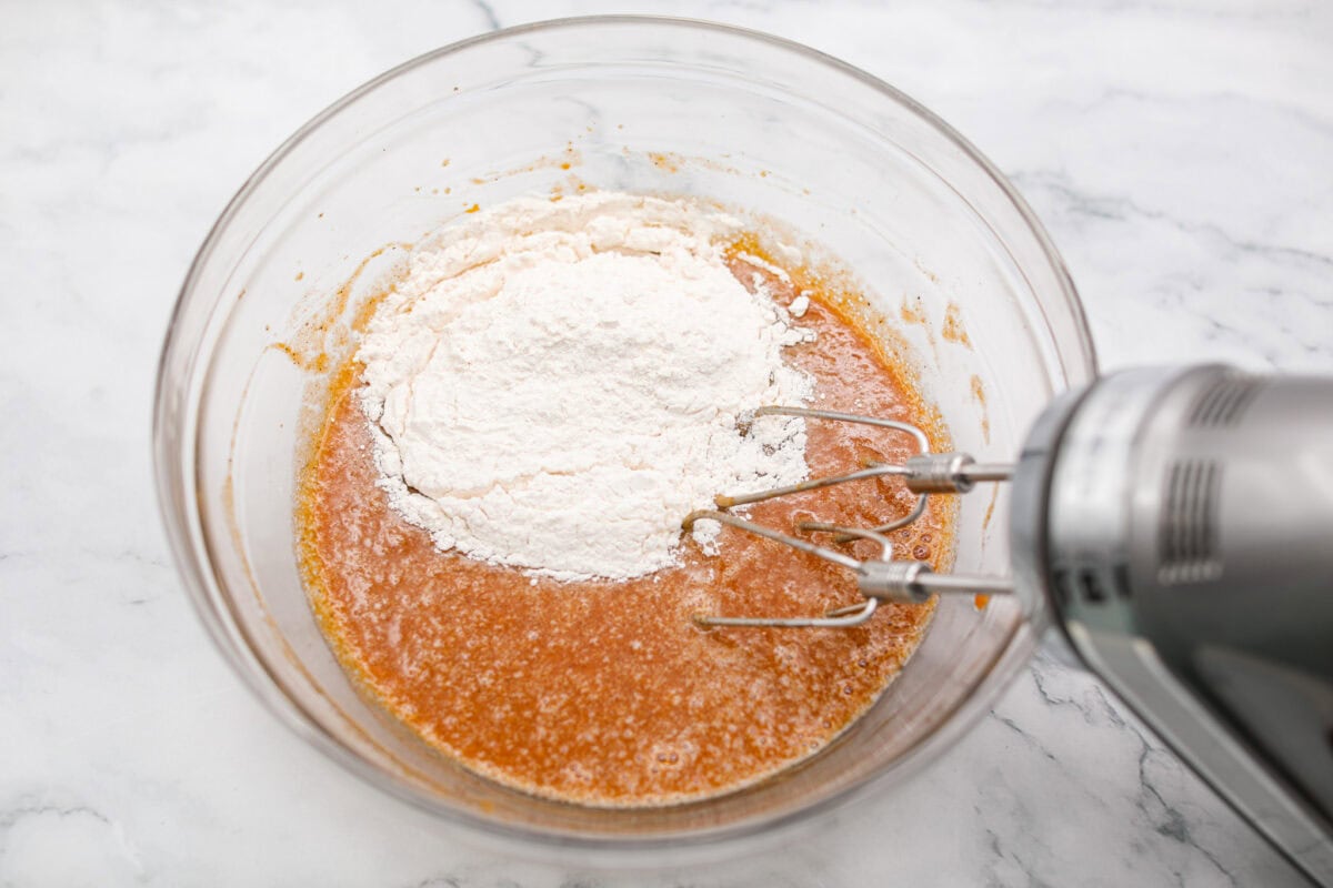 This really is the world’s best pumpkin roll! Soft, moist pumpkin cake wrapped around a sweet cream cheese filling and finished with a dusting of powdered sugar, it’s pure fall magic. The best part? It’s surprisingly easy to make. Dry ingredients being added to the wet ingredients.