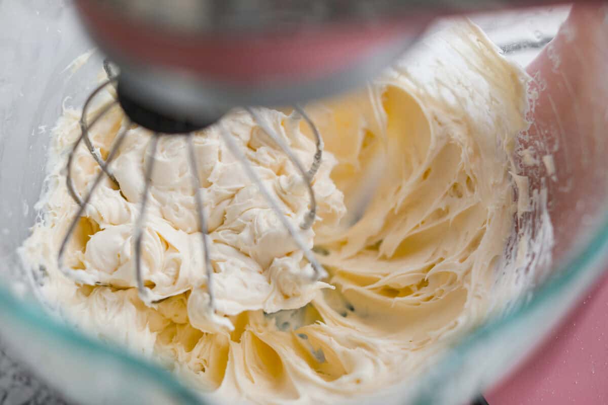 This really is the world’s best pumpkin roll! Soft, moist pumpkin cake wrapped around a sweet cream cheese filling and finished with a dusting of powdered sugar, it’s pure fall magic. The best part? It’s surprisingly easy to make. Cream cheese filling ingredients being mixed together in a stand mixer.