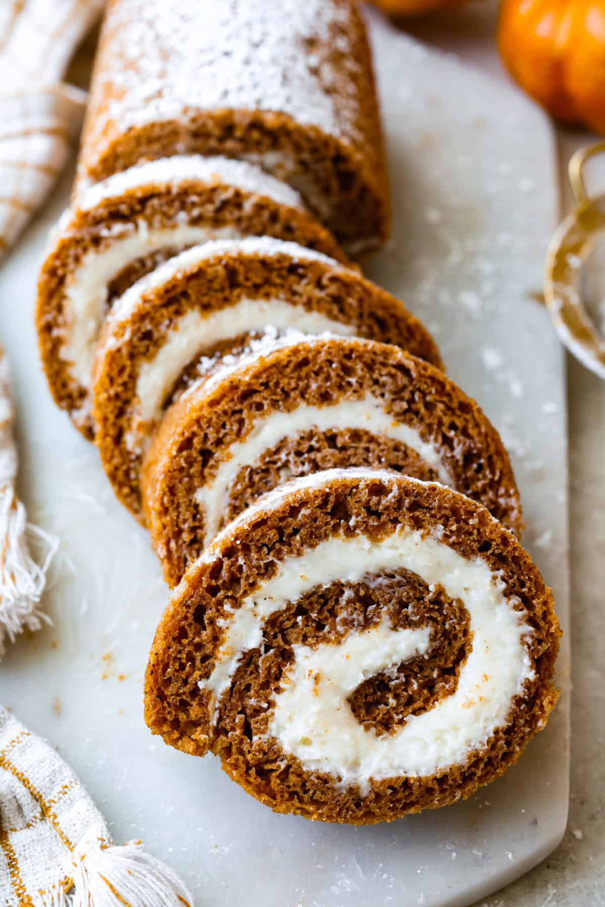 This really is the world’s best pumpkin roll! Soft, moist pumpkin cake wrapped around a sweet cream cheese filling and finished with a dusting of powdered sugar, it’s pure fall magic. The best part? It’s surprisingly easy to make. Sliced up pumpkin roll cake.