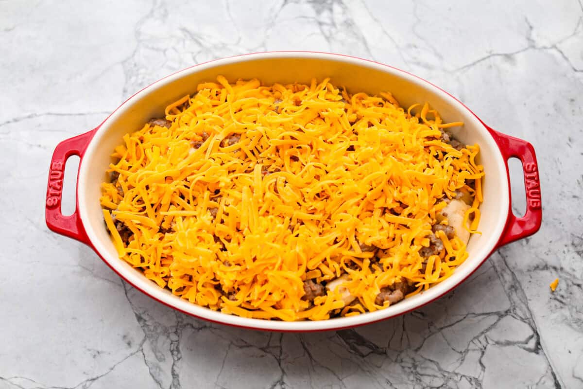 Wake up to a breakfast that feels like a warm hug! This Christmas morning casserole turns sausage, eggs, cheese, and fluffy biscuits into the easiest, hearty breakfast you can't get enough of! Cheese sprinkled over the top of the sausage and biscuits.