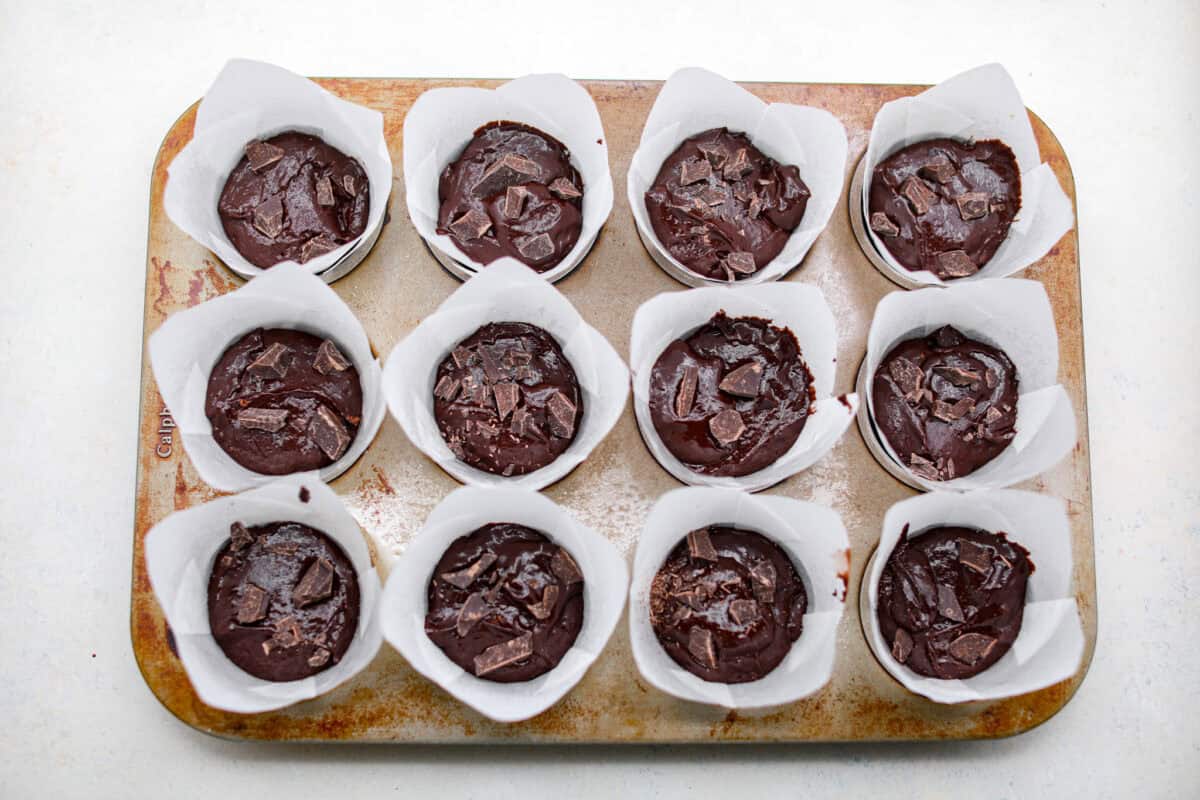 Overhead shot of the chocolate muffin batter in each muffin liner in the muffin tin. 