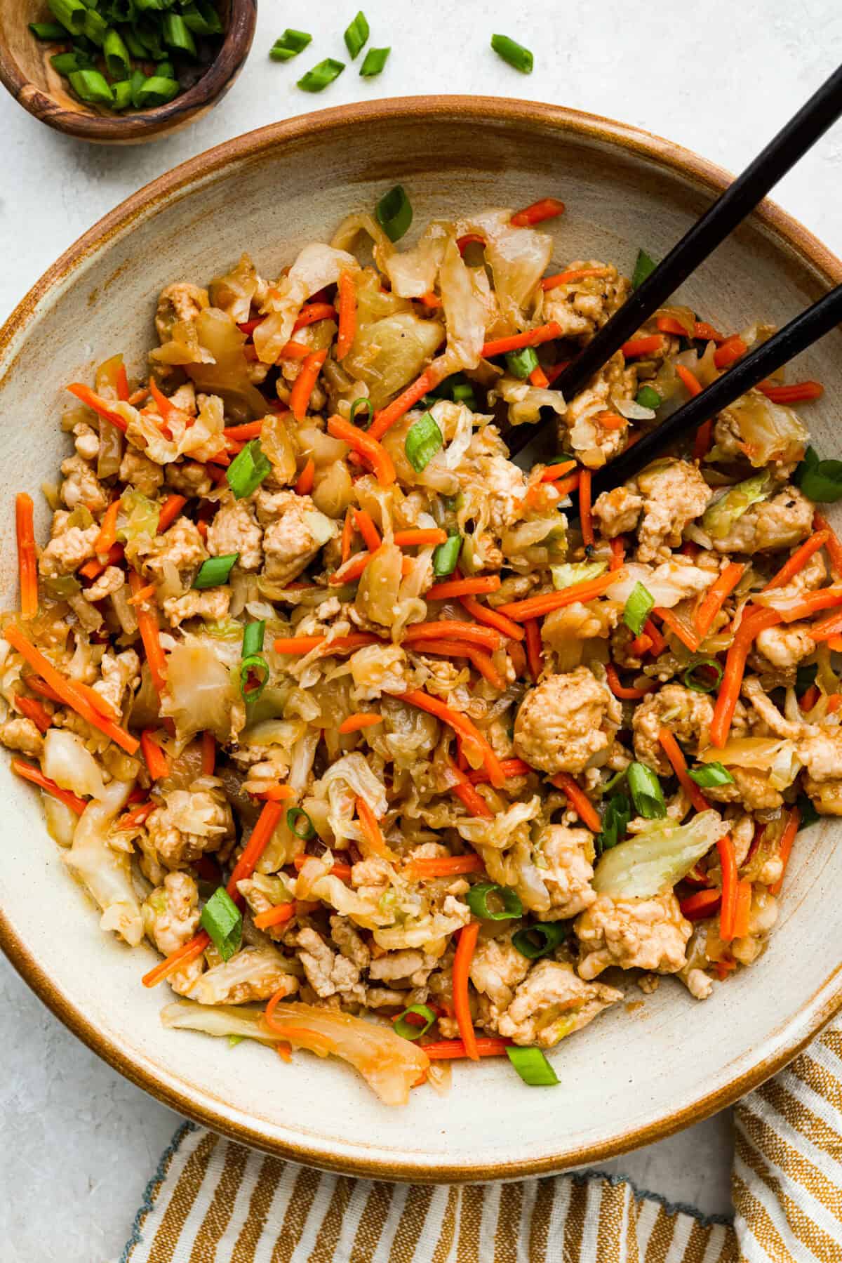 If you haven’t tried egg roll in a bowl yet, you’re in for a treat. Everything you love inside of an egg roll in a lighter, healthier, no-wrapper version! It's ready in 15 minutes, making it a perfect weeknight meal! Serving portion of egg roll in a bowl with chopsticks.