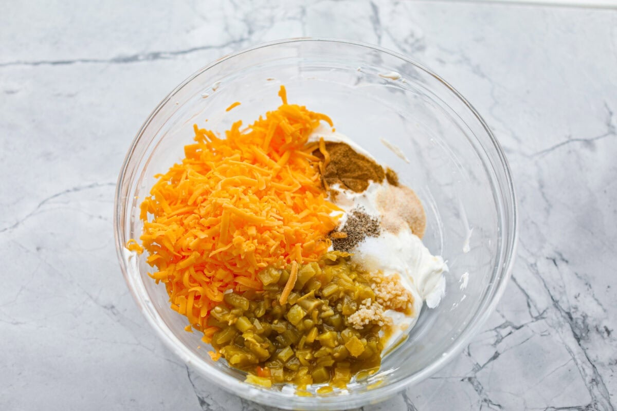 This green chile dip is warm, creamy, and so easy! The best part is, you get to control the heat! I'm telling you, the flavor hits bigger than the ingredient list! Make this for your next get-together, or let's be real, lunch! Cheese, chiles, and seasonings added to the bowl.