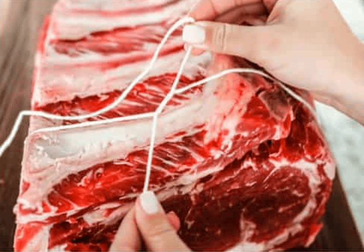 I have the perfect fool proof prime rib recipe for you. I have done all of the testing for you so that you can achieve the perfect prime rib every single time. Melt in your mouth, cooked perfectly to medium rare with a perfect garlic butter crust, this recipe is incredible. I will help you feel confident every step of the way! Someone tying the prime rib with butchers twine.
