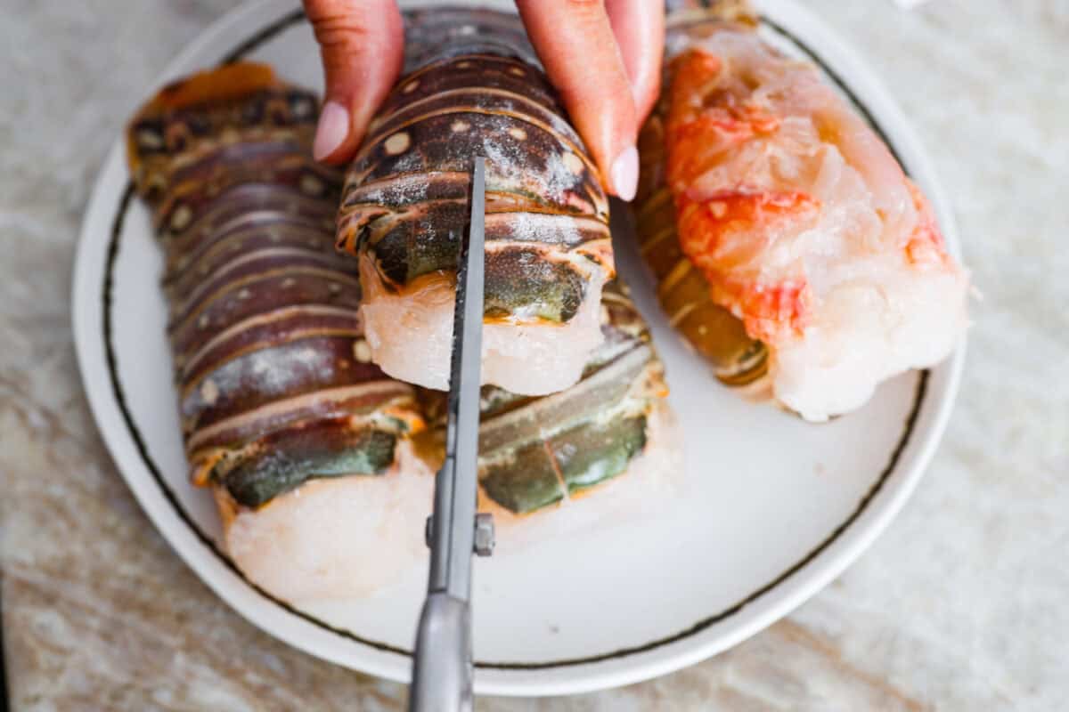 Instant pot lobster is the easiest way to bring a little luxury to your dinner table, no boiling pots or fancy techniques needed! In just minutes, the lobster cooks up tender, juicy, and perfectly steamed, ready to soak up a rich garlic herb butter. Someone cutting the shell on the top of the lobster tail with kitchen sheers.