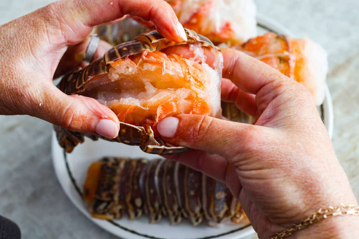 Instant pot lobster is the easiest way to bring a little luxury to your dinner table, no boiling pots or fancy techniques needed! In just minutes, the lobster cooks up tender, juicy, and perfectly steamed, ready to soak up a rich garlic herb butter. Someone using their hands to lift the lobster tail meat up.