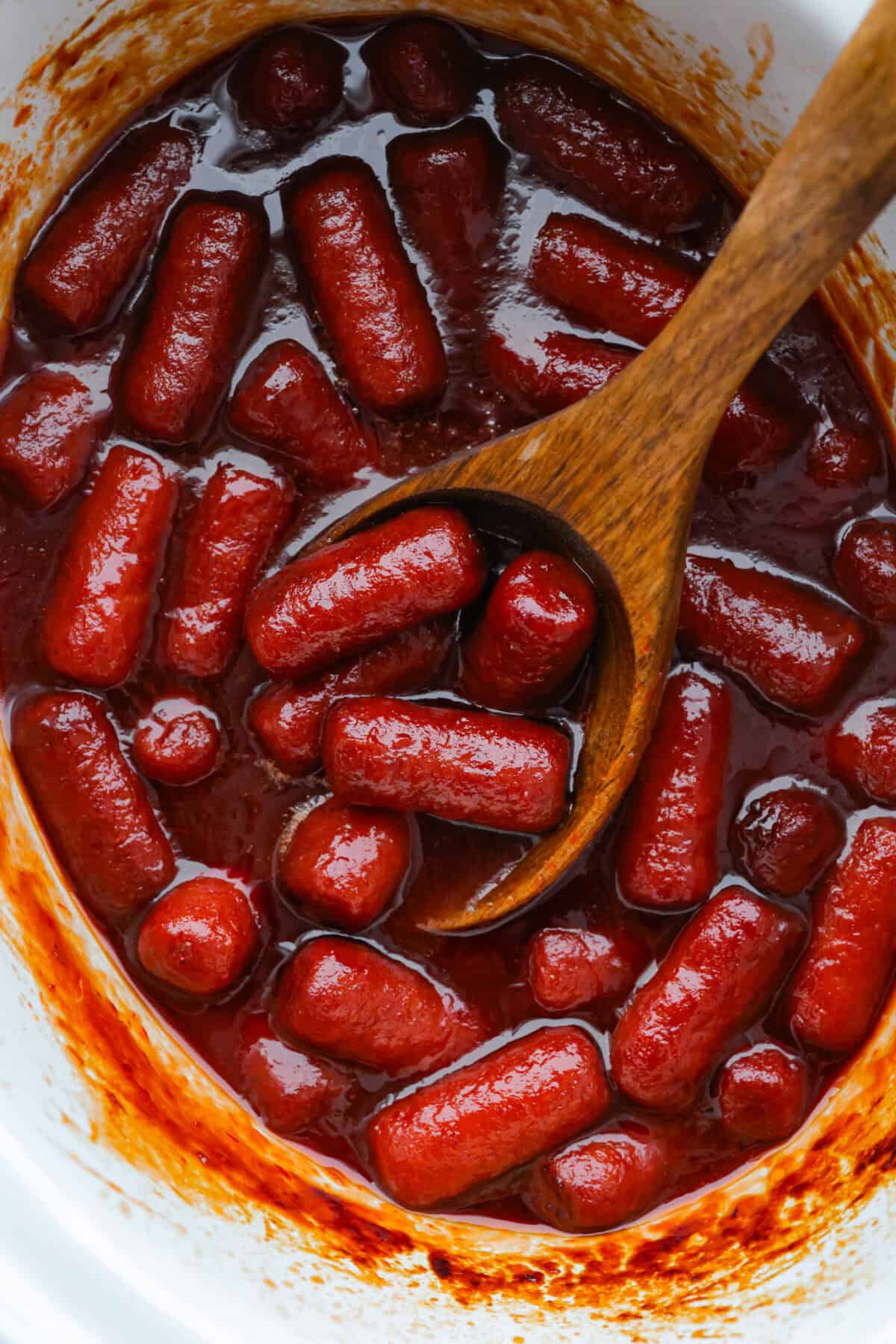 If you’re hosting anything and need a quick appetizer, these crockpot grape jelly little smokies are it. Dump everything in the slow cooker, walk away, and come back to glossy, flavorful sausages that people hover around all night. Crockpot grape jelly little smokies in a slow cooker with a large wooden spoon.