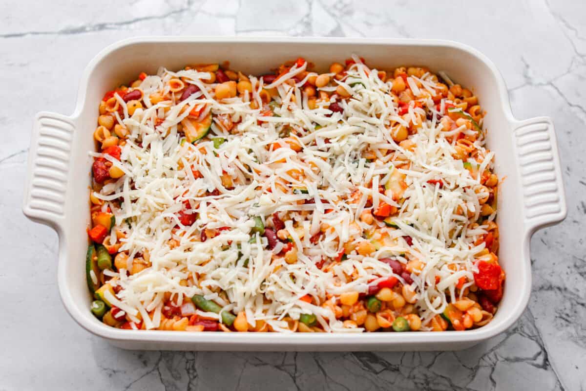 If you love my minestrone soup even a little, you have to try this minestrone casserole. It takes the cozy, veggie packed soup you already love and turns it into a hearty, cheesy pasta bake. It feels like weeknight dinner perfection. All of the ingredients mixed together and spread out in a casserole dish and topped with cheese.
