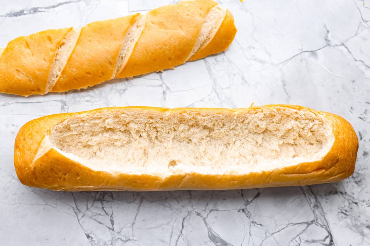 Loaf of french bread cut in half the long way and the bread pulled out of the middle. 