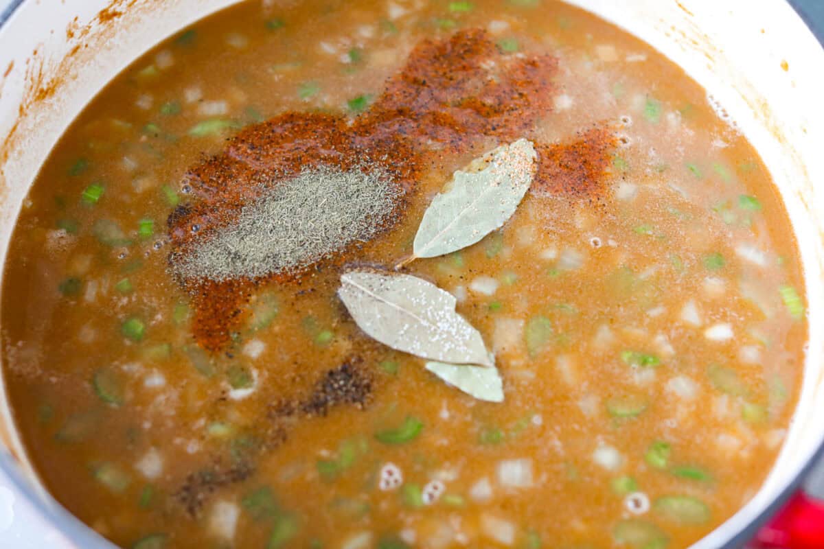 After listening to your feedback and learning what makes a great New Orleans gumbo, I made some changes. This version is richer, more balanced, and way closer to the real deal, without being overwhelming to make at home. Bay leaves and seasonings added to the pot full of ingredients.