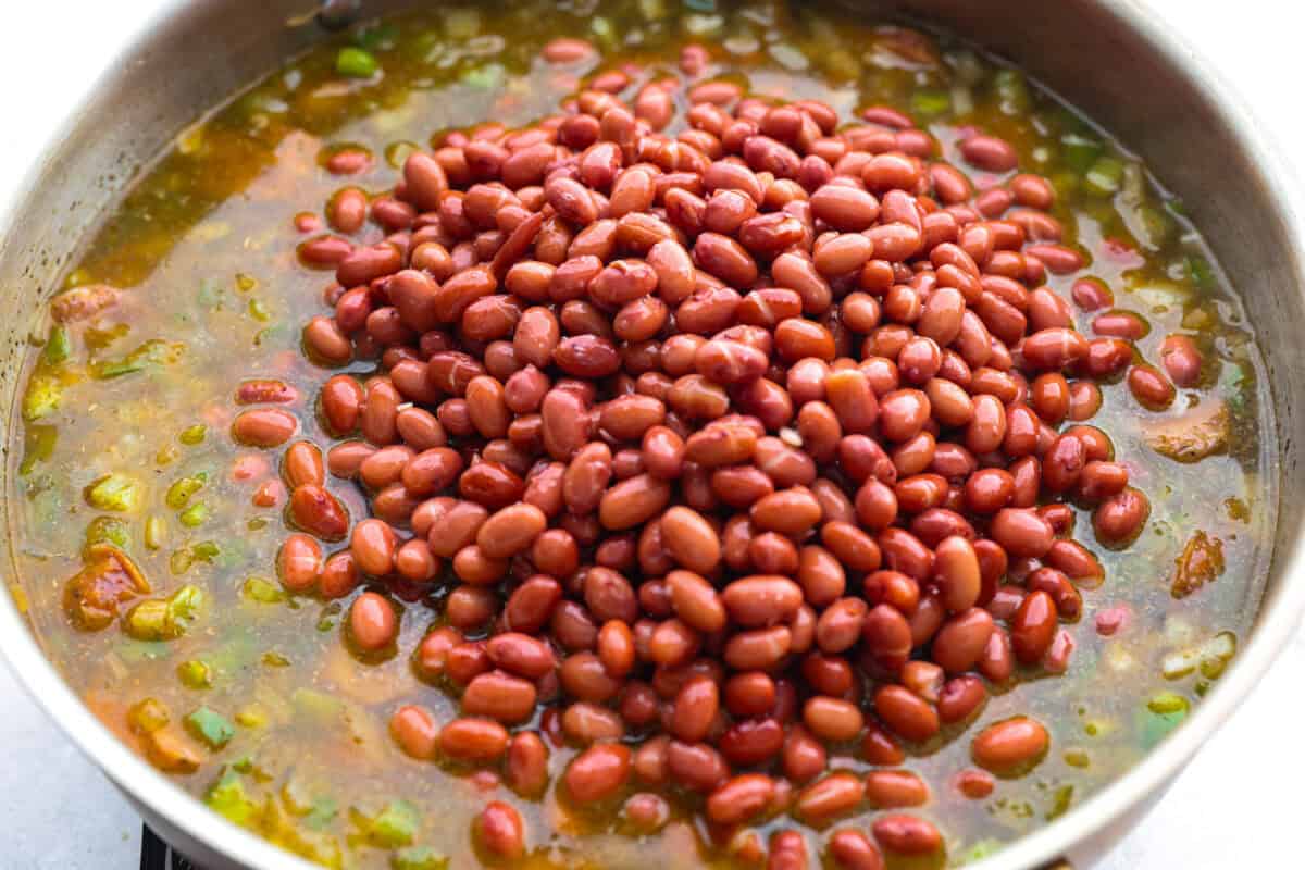 If your family is hungry now and you don't have time to soak beans or babysit the stove, this red beans and rice is for you. It is quick, cozy, and made with canned beans and smoky sausage. It tastes great and is ready fast! Beans and broth added to the skillet.