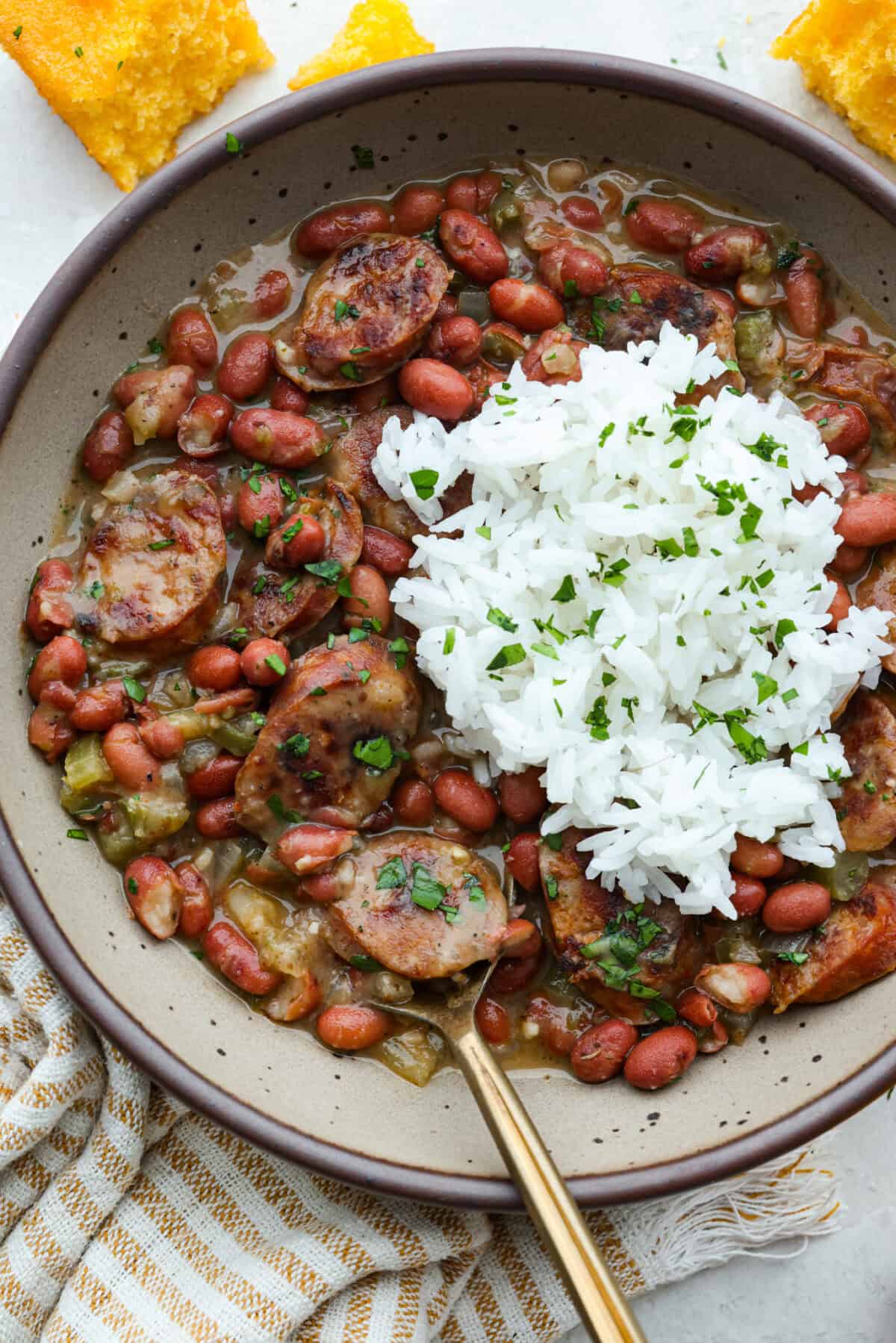 If your family is hungry now and you don't have time to soak beans or babysit the stove, this red beans and rice is for you. It is quick, cozy, and made with canned beans and smoky sausage. It tastes great and is ready fast! Bowl of red beans and rice with a scoop of rice on top.