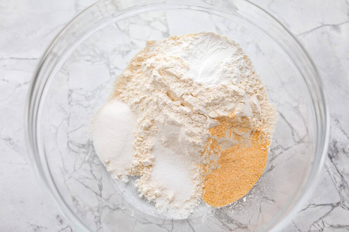 If you love my Red Lobster Biscuits, this Cheddar Bay Biscuit Bread has the same buttery, garlicky cheddar flavor, just mixed and baked right in a bread pan. Slice it warm and serve it with basically anything. It's a must-make! Trust me! Mixing bowl full of dry ingredients.