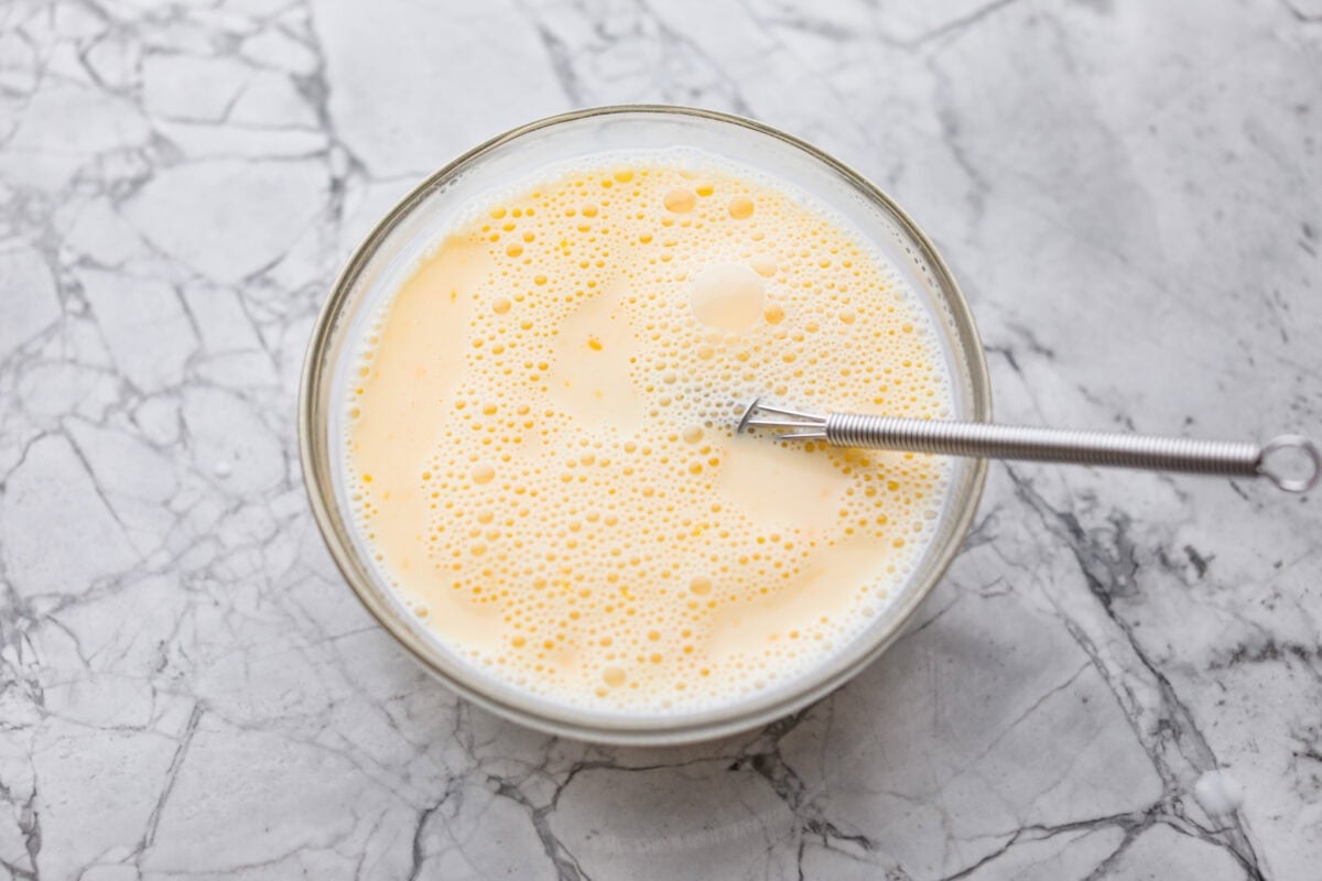 If you love my Red Lobster Biscuits, this Cheddar Bay Biscuit Bread has the same buttery, garlicky cheddar flavor, just mixed and baked right in a bread pan. Slice it warm and serve it with basically anything. It's a must-make! Trust me! Bowl of milk and egg whisked together.