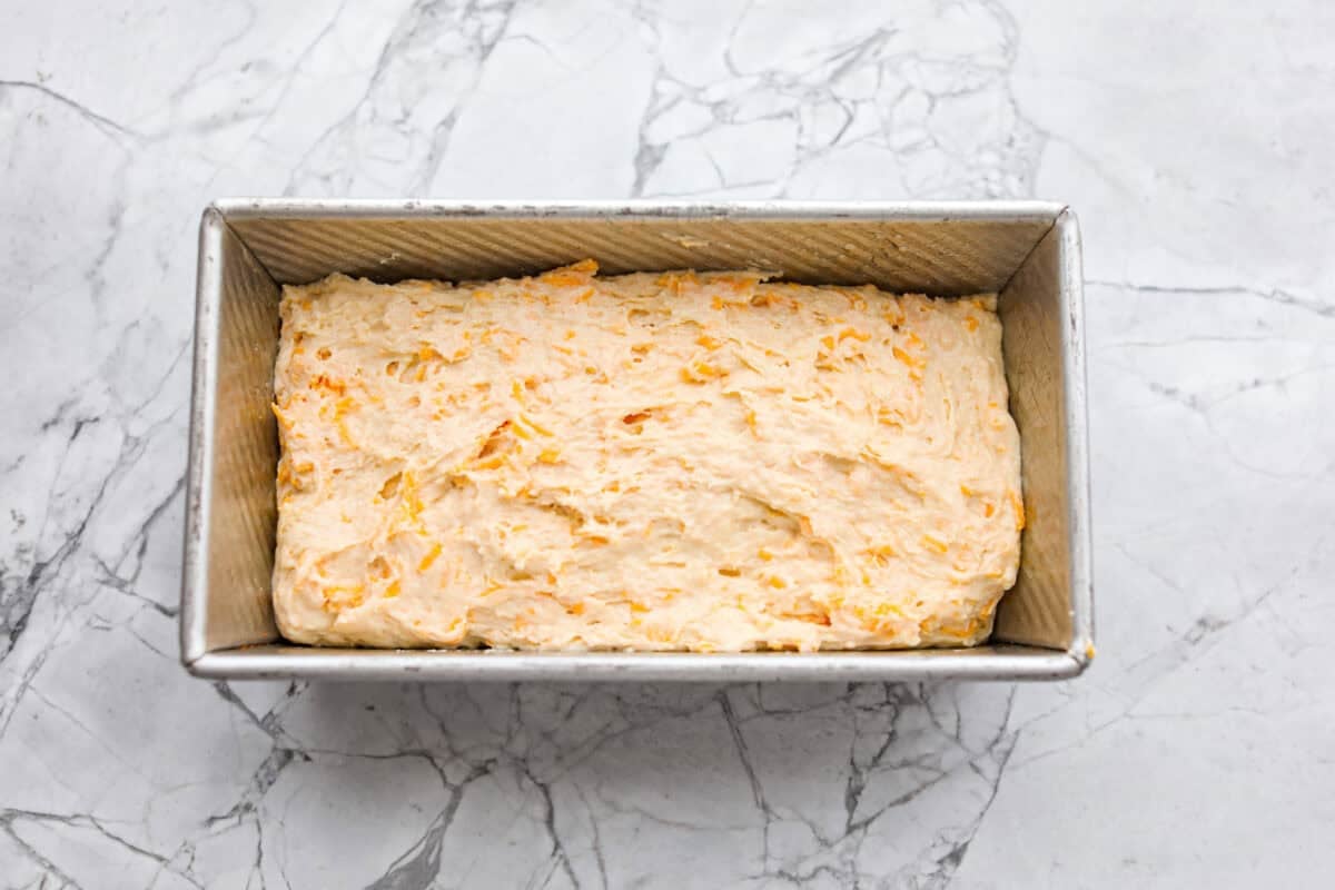 If you love my Red Lobster Biscuits, this Cheddar Bay Biscuit Bread has the same buttery, garlicky cheddar flavor, just mixed and baked right in a bread pan. Slice it warm and serve it with basically anything. It's a must-make! Trust me! Cheddar bay biscuit bread batter added to the loaf pan.