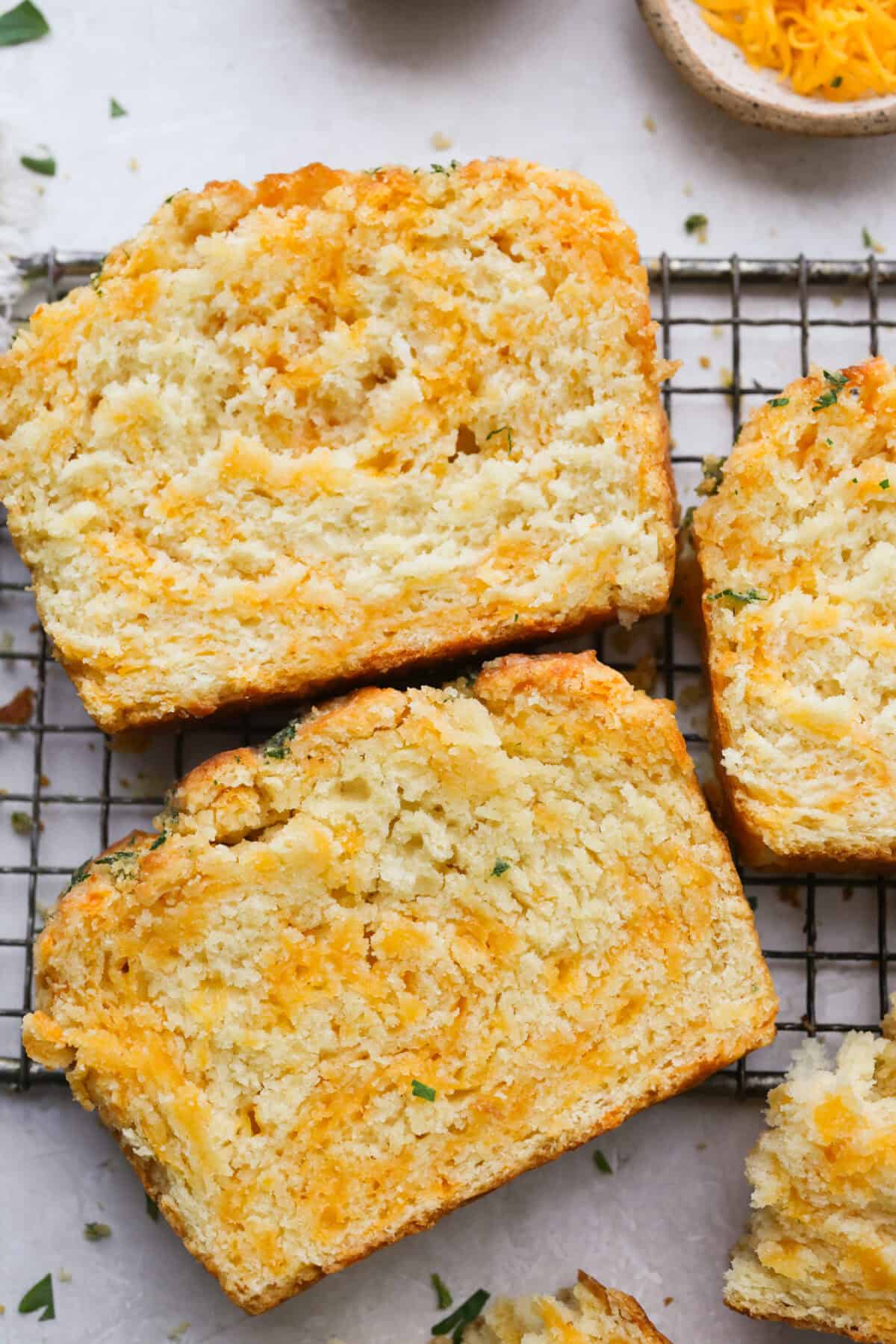 If you love my Red Lobster Biscuits, this Cheddar Bay Biscuit Bread has the same buttery, garlicky cheddar flavor, just mixed and baked right in a bread pan. Slice it warm and serve it with basically anything. It's a must-make! Trust me! Slices of the cheddar bay biscuit bread.