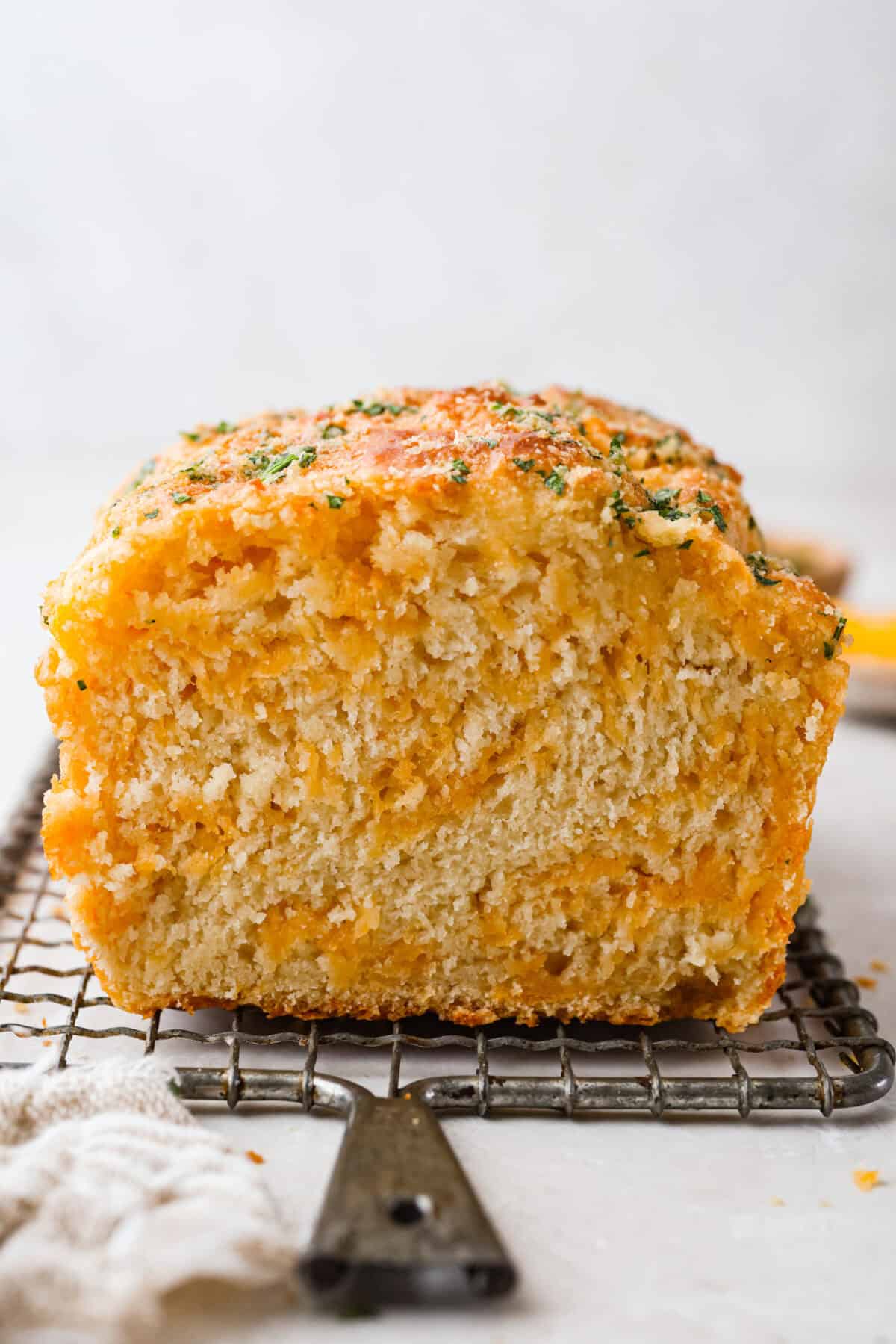 If you love my Red Lobster Biscuits, this Cheddar Bay Biscuit Bread has the same buttery, garlicky cheddar flavor, just mixed and baked right in a bread pan. Slice it warm and serve it with basically anything. Cheddar bay biscuit bread loaf cut in half on a cooling rack.